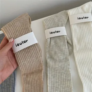 Gros plan de chaussettes montantes côtelées unies avec détail de bande en papier, tricot doux.