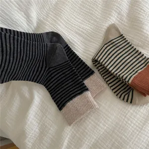 Close-up detail shot of striped slouch socks with contrast color cuffs, soft knit texture.