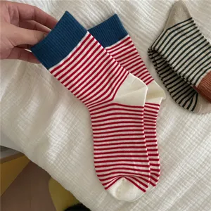 Close-up detail of women's red and white striped mid-tube socks with blue color-block cuffs.