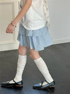 Vue détaillée de chaussettes blanches montantes associées à des chaussures noires et jupe.