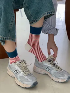 Close-up of stylish striped mid-calf socks featuring blue cuffs and red white pattern for daily wear.