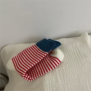 Cozy women's mid-calf socks featuring vibrant red and white stripes with a stylish blue cuff.