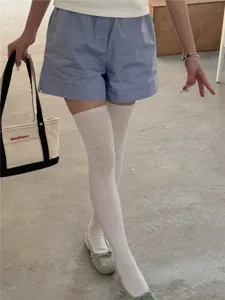 Vue détaillée des chaussettes hautes blanches montrant une texture respirante et stylée.