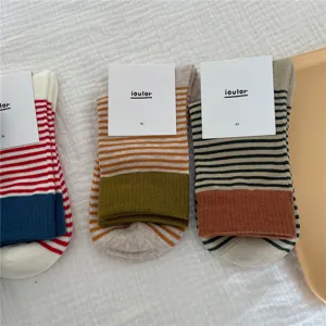 Close-up detail of cozy striped mid-calf socks featuring stylish color-blocked cuffs.