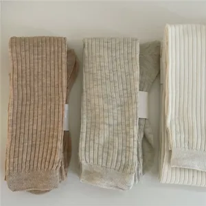 Vue rapprochée de trois bas plissés côtelés de teintes neutres, texture en tricot doux et souple.