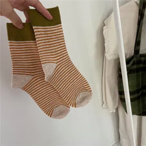 Close up of colorful striped mid-calf socks with contrast green ribbed cuff and soft toe.