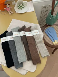 Detailansicht dicker Woll-Beinwärmer für den Winter, Vintage-Strickdesign, gemütliches Tisch-Set.
