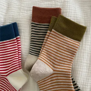 Detailed shot of women's cozy striped mid-calf socks with contrast ribbed cuffs, soft knit.