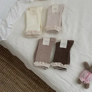 Détail de chaussettes montantes côtelées pour femme avec volants de dentelle, style ballet.