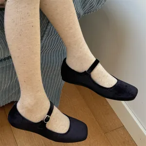 Detailed close-up of speckled tights worn with black velvet shoes in an indoor setting.