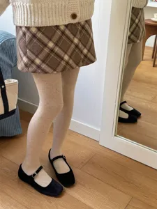 Close-up view of speckled light-colored footed tights paired with cozy knit wear and shoes.