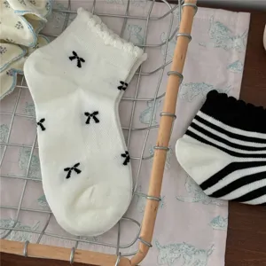 Dettaglio in primo piano di calzini corti con fiocco e righe da donna in cesto di filo.