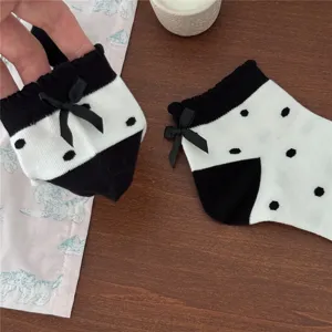 Primo piano di calzini corti da donna a pois bianchi e neri con grazioso fiocco.