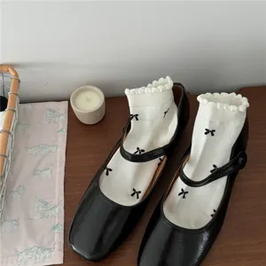 Scarpe Mary Jane nere abbinate a calzini bianchi con volant e fiocchi in stile kawaii.