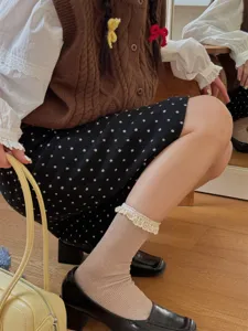 Vue détaillée de chaussettes mi-mollet beiges avec de délicats volants en dentelle.