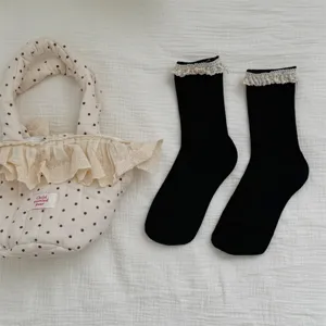 Gros plan de chaussettes noires mi-jambes avec de jolis volants en dentelle blanche.