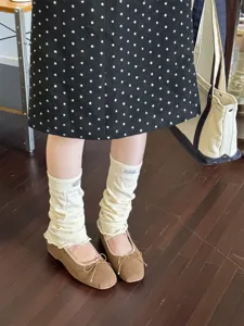 Detail view of cozy white knit leg warmers with ruffle edge and cute brown flats.
