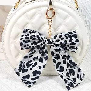 Gros plan élégant sac rond blanc avec porte-clés nœud en tissu imprimé léopard noir et blanc.