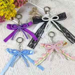 Detail shot of handmade double-layer bow keychains with faux pearls and lace trims.