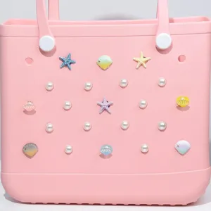 Close-up detail view of pink EVA beach bag decorated with cute pearl and seashell charms.