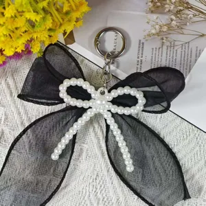 Close-up detail of a handmade black organza double bow keychain with faux pearls.