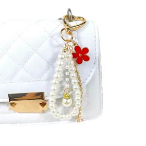 Perlenperlen Schlüsselanhänger mit roter Blume und Eiffelturm Anhänger an weißer Tasche.