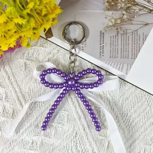 Purple pearl bow keychain detail with white lace ribbon and metal ring, sweet style.