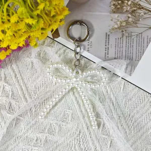 Close-up of a sweet handmade imitation pearl double-layer bow keychain with lace pendant.