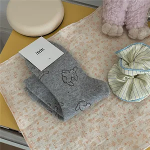 Close-up detail of cute grey dog print mid-tube socks with packaging tag on fabric.