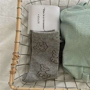 Detailed view of grey specked crew socks with brown embroidered cute bear pattern in basket.
