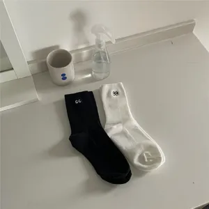 Chaussettes mi-hautes en coton avec yeux brodés noirs et blancs, style minimaliste.
