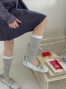 Detail shot of gray stirrup socks with white ribbed cuffs worn with silver flats.