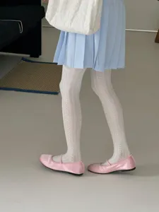 Gedetailleerd overzicht van witte patroonpanty's gecombineerd met rok en platte schoenen.