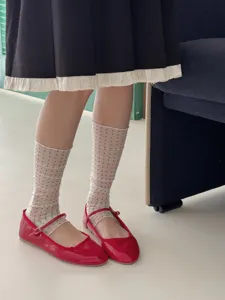 Sheer polka dot socks paired with red patent leather Mary Jane flats, stylish detail view.