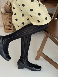 Gedetailleerd shot van stijlvolle zwarte panty's met patronen gedragen met schoenen en rok.