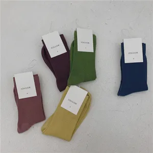 Gros plan de chaussettes mi-hautes en coton unies aux coloris vifs avec étiquettes de marque.