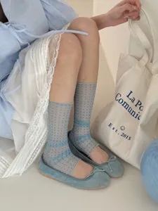 Close up of sheer blue polka dot leg warmers with ribbon straps, lifestyle detail shot.