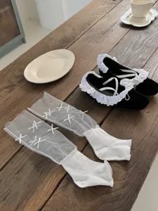 Detailopname van witte mesh sokken met strikken en zwarte schoenen voor de zomer.