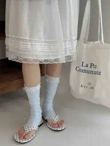 Close-up detail shot of light blue ribbed socks styled with a white lace skirt and cute sandals.