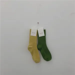 Vue détaillée de chaussettes côtelées suspendues au mur, aux couleurs jaune et verte en coton doux.
