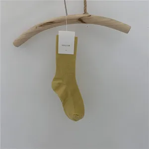 Vue détaillée de chaussettes unies mi-hautes élégantes suspendues à un cintre en bois.