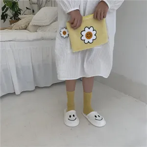 Joli sac en peluche marguerite souriante assorti à des chaussettes jaunes douillettes.