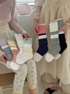 Detail shot of multiple color variants of Korean style ruffle trim stirrup leg warmers with cards.