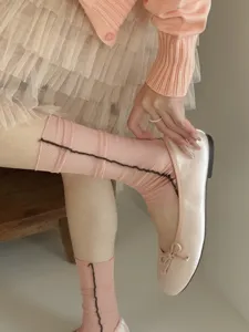 Close-up detail of sheer pink summer socks featuring a stylish dark vertical seam and breathable fabric.