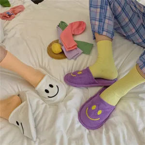 Detailansicht von lässigen Baumwoll-Socken und Smile-Hausschuhen auf gemütlichem Bett.