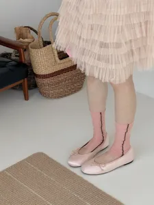 Detail view of sweet pink tiered skirt paired with ballet flats and socks for women.