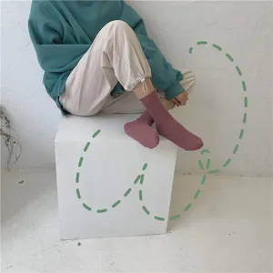 Vue détaillée de chaussettes mi-hautes côtelées unies portées par un mannequin en studio.
