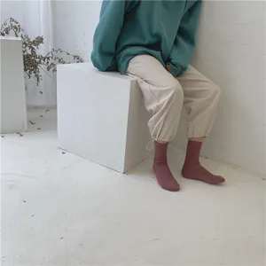 Vue détaillée de chaussettes en tricot unies mi-mollet dans un décor minimaliste.