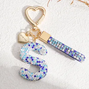 Détail du porte-clés lettre S en strass avec des cristaux bleus et un pendentif.