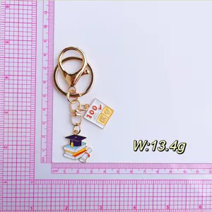 Graduation keychain detail showing metal cap books and full score test paper pendant close up
